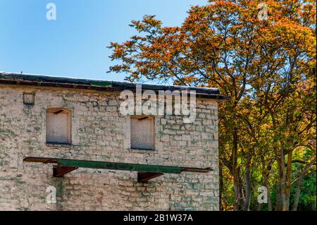 Windows boarded up and a steel and wood platform on the side of an old building. Stock Photo