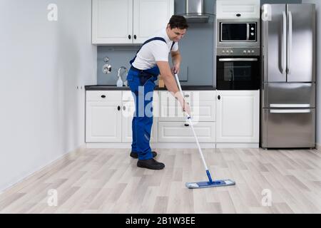 Man Cleaning Floor With Mop In Kitchen At Home Stock Photo