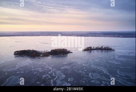 Small islands on frozen lake aerial drone view in winter time Stock Photo