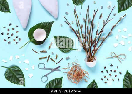 Ears of a hare, branches with kidneys, eggshells, green leaves, scissors on a light background. Easter spring flat-lay concept. Stock Photo