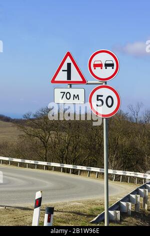 Road signs, speed limits and ban on overtaking at a sharp turn of the highway. The rules of the road Stock Photo