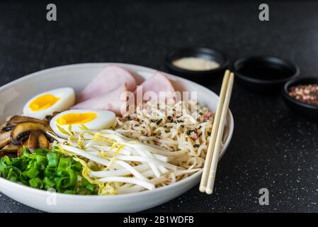 A bowl of asian food ramen noodles soup against black stone background. Stock Photo