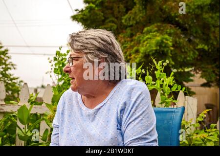 Woman with serious expression listening to son while sitting in her backyard in Ludington, Michigan, USA. Stock Photo