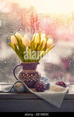 Golden Easter Eggs in ceramic egg tray with tulip on white table ...