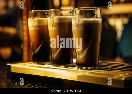 Dublin, Ireland, December 2017 Selective focus on three pints of Guinness in glasses on bar or tap. Guinness is iconic Irish beer Stock Photo