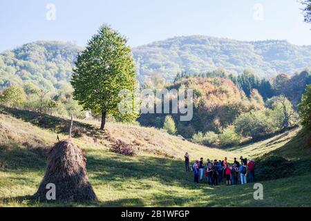Group of hikers take a break on beautiful green rural  fields on summer day. Hiking Adventure Exploring Stock Photo