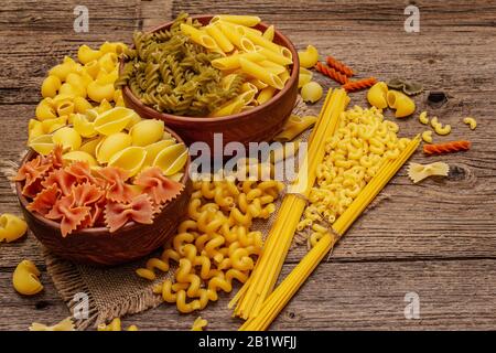 Different types of pasta in ceramic bowls. Traditional Italian food, healthy eating concept. Rustic wooden table, close up Stock Photo
