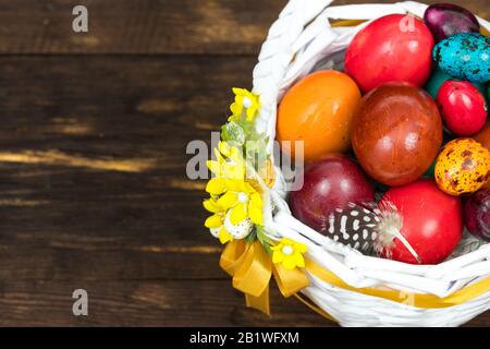 Happy Easter. Traditionally, colorfully painted eggs in a basket. Background of old boards, festive decor / Place for text Stock Photo