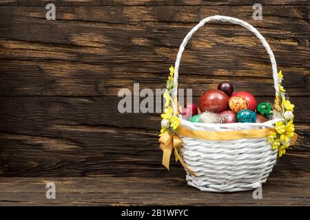 Happy Easter. Traditionally, colorfully painted eggs in a basket. Background of old boards, festive decor / Place for text Stock Photo