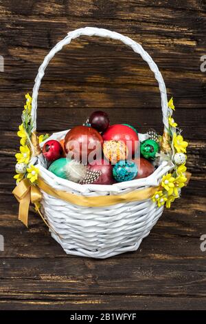 Happy Easter. Traditionally, colorfully painted eggs in a basket. Background of old boards, festive decor / Place for text Stock Photo