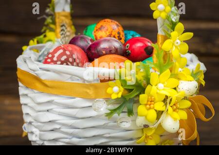 Happy Easter. Traditionally, colorfully painted eggs in a basket. Background of old boards, festive decor Stock Photo