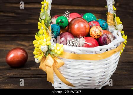 Happy Easter. Traditionally, colorfully painted eggs in a basket. Background of old boards, festive decor Stock Photo