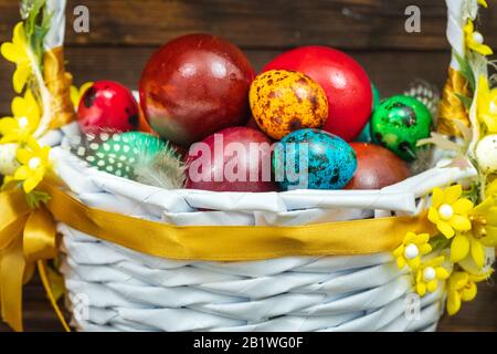 Happy Easter. Traditionally, colorfully painted eggs in a basket. Background of old boards, festive decor Stock Photo