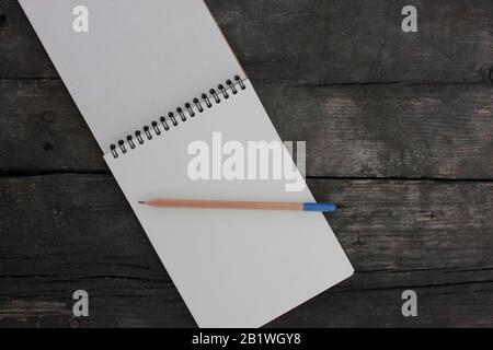 Open paper notepad on spiral and pencil on rough textured wooden table. Top view Stock Photo