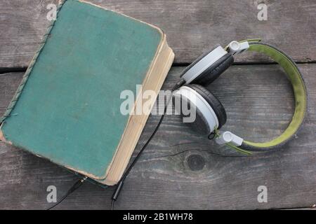 Old shabby book on a rough wooden table covered with moss outdoors. Top view, copy space Stock Photo