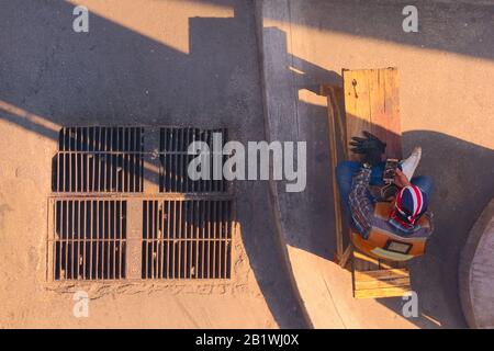 Construction worker resting in the shade and using his smartphone during a break in Bangkok, Thailand. Top down view. Stock Photo