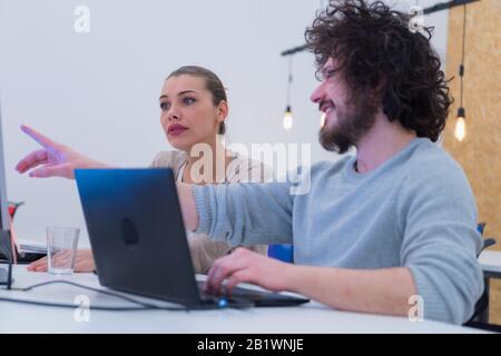 Two Creative office workers collaborate together to discuss main ideas for creating businness investment plan, analyze presentation on laptop computer Stock Photo