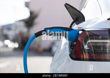 EV electric car pluged charging at a recharge station in the city Stock Photo