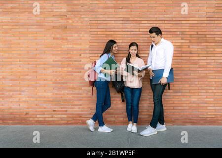 Three Asian students are discussing about exam preparation, presentation, study, study for test preparation in University. Education, Learning, Studen Stock Photo