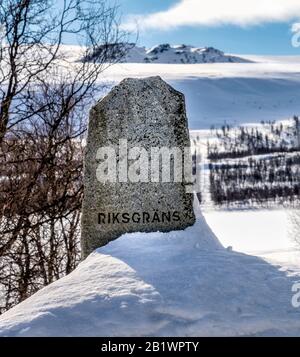 The boundary aged stone on Sweden Norway state border in mountains, forest wide swath marking it, close up view, beautiful sunny day Stock Photo