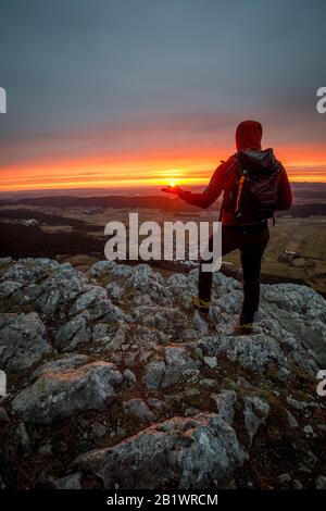 Hiker with backpack relaxing on top of a mountain and enjoying valley ...