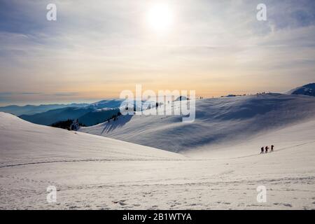 Hikers silhouette at dawn on Mount Ciucas in winter watching the sunset, part of Romanian Carpathian Range Stock Photo