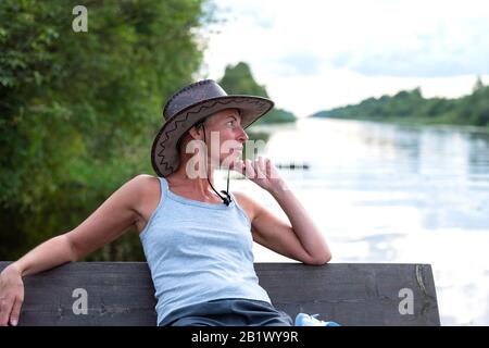 A woman in a cowboy hat, in nature. Near water. Stock Photo