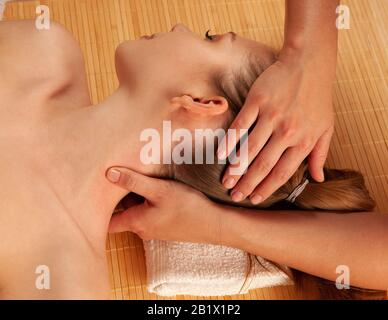 Beautiful young woman having a face massage in spa salon - wellness . Stock Photo