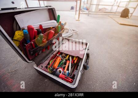 toolbox full of hand tools on real dusty floor background at construction site Stock Photo
