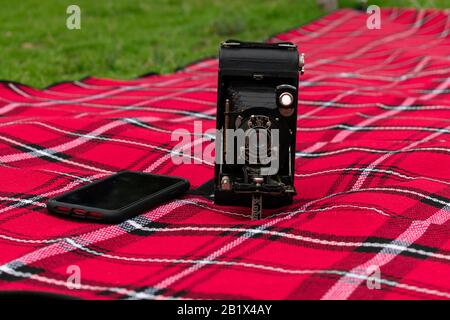 old camera with a modern camera phone on a picnic rug Stock Photo