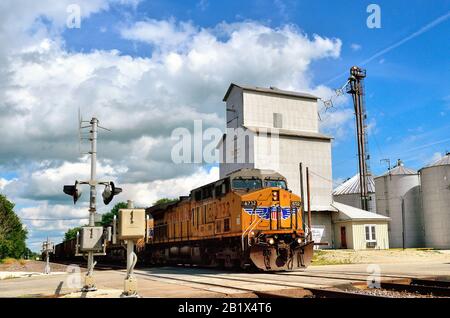 Creston, Illinois, USA. A Union Pacific empty coal train, lead by three locomotive units passing a grain elevator and grade crossing. Stock Photo