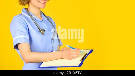 nurse in medical coat with documents writes important information. nurse writing some data into the folder of papers. Female hospital administrative in a modern medical center. copy space. Stock Photo