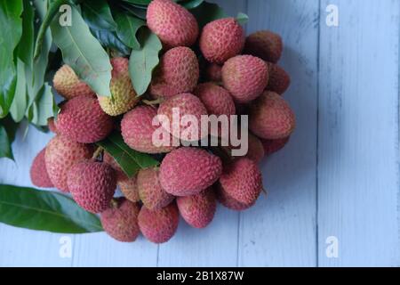 fresh lychee with leaves on wooden background Tropical fruit Stock Photo