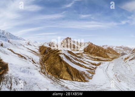 the gravel road on dry land with the snow mountain Stock Photo