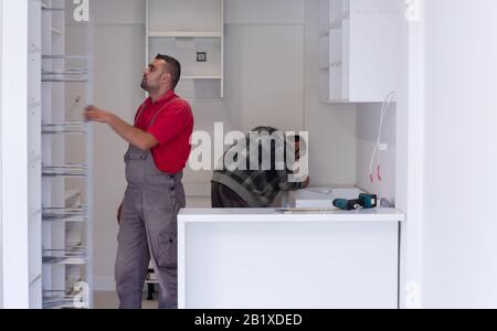 two professional workers installing a new stylish modern kitchen furniture Stock Photo