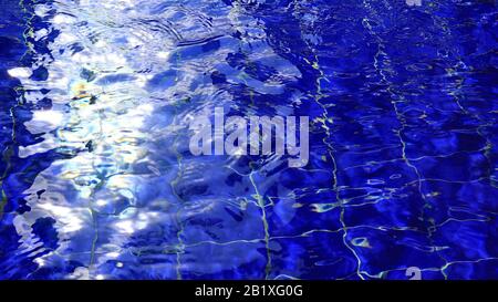 Background of swimming poll water with ripple and sun reflections on a surface. Stock Photo