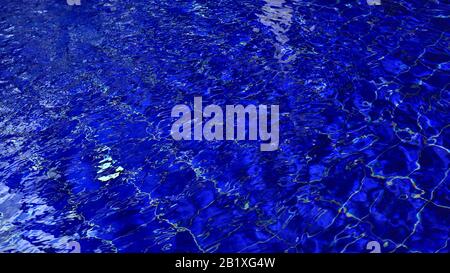 Background of swimming poll water with ripple and sun reflections on a surface. Stock Photo