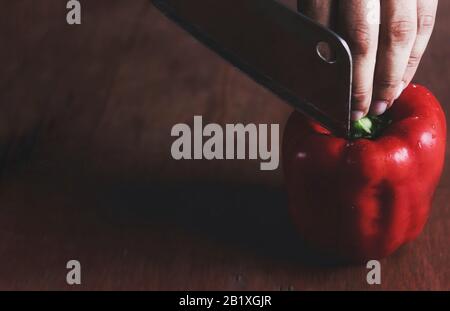 Minimalist still life of a red paprika (bell pepper) being sliced to show the concept of culinary, cuisine, gastronomy and the food service industry Stock Photo