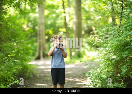 Young boy taking photo in the forest. Stock Photo