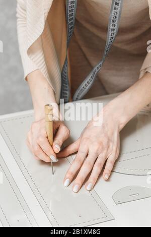 Leather craftswoman working making measurements in patterns at table in workshop studio. Small business and mastership concept Stock Photo