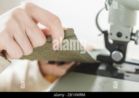 Young white woman stitching leather using a sewing machine Stock Photo