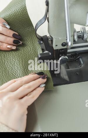 Young white woman stitching leather using a sewing machine Stock Photo