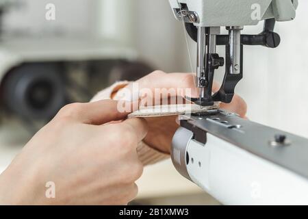 Young white woman stitching leather using a sewing machine Stock Photo