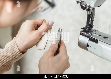 Young white woman stitching leather using a sewing machine Stock Photo