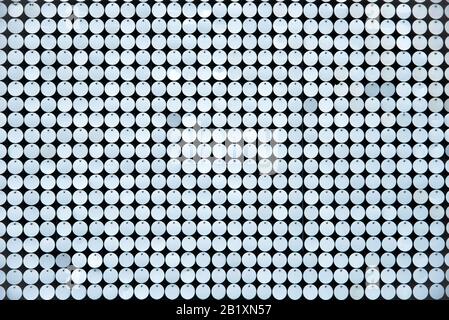 Rows of small shiny metallic disks viewed from the top on dark background texture effect in full frame Stock Photo