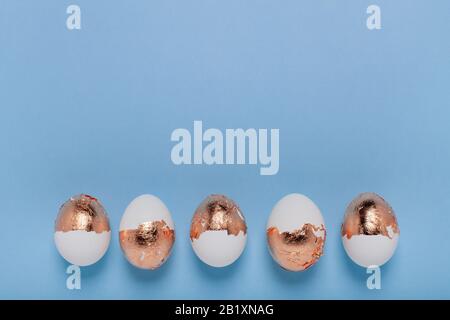 Minimalistic background. Golden eggs are arranged in a straight line. Stock Photo