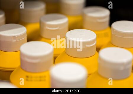 Close up / macro of plastic bottles with white cap and yellow body. The bottles contain mustard. Stock Photo