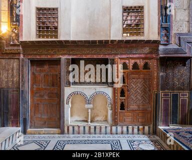 Wooden painted floral patterns, embedded arched niche, wooden door, wooden engraved cupboard, calligraphy decoration, and marble floor with geometric pattern at El Sehemy ottoman era historic house  Stock Photo