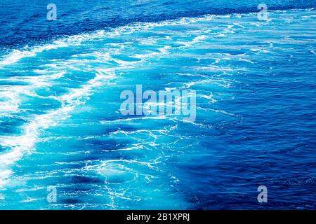 Trail on ocean water surface behind of fast moving powerful ship engines. Stock Photo