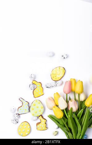 Easter homemade gingerbread cookies with icing, decorated eggs and tulips on a white background/ Happy easter concept. Copy space, flat lay, Template Stock Photo